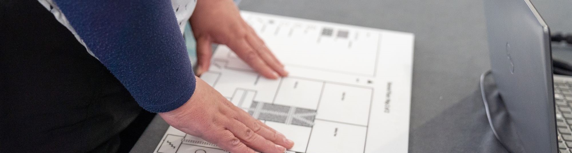 Hands explore a tactile concept map of the Museum