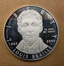 One side of the Braille silver dollar coin
